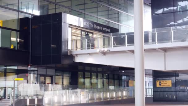 La gente camina en la pasarela pertinente que conduce a la entrada de vidrio moderno en la Terminal 2 del aeropuerto de Heathrow - 4K — Vídeos de Stock