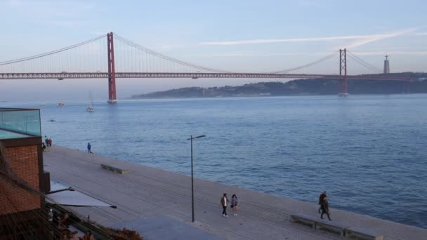 Peatones frente al icónico puente 25 de abril en Lisboa, Portugal — Vídeo de stock