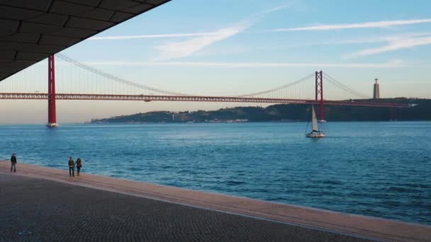 Pedoni vicino al fiume Tago, Lisbona, Portogallo incorniciato dall'architettura del MAAT Museum al tramonto — Video Stock