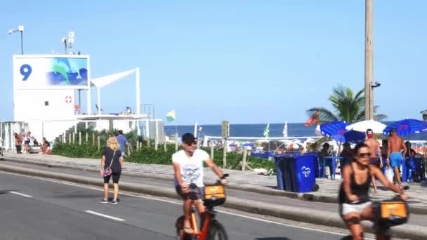 Cariocas och turister promenad på Posto 9 avsnitt av den ikoniska Ipanema beach på en söndag eftermiddag - 4k — Stockvideo
