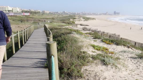 As pessoas passeiam no calçadão de madeira perto da praia do Espinho, Portugal — Vídeo de Stock