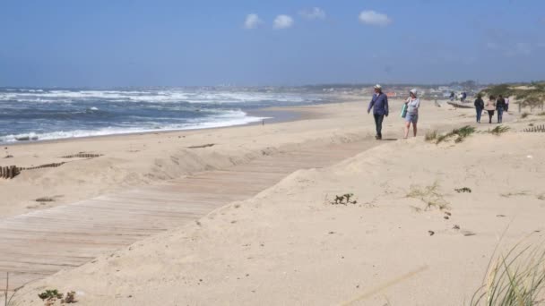La gente pasea por el paseo marítimo de madera cerca de la playa de Espinho, Portugal — Vídeos de Stock