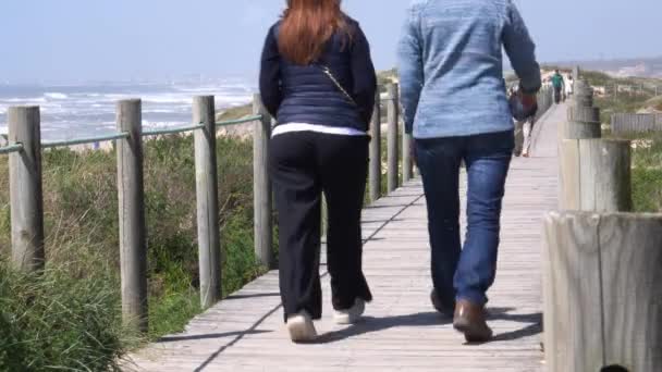 As pessoas passeiam no calçadão de madeira perto da praia do Espinho, Portugal — Vídeo de Stock