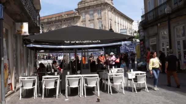 La gente se sienta en las terrazas de la cafetería en una tarde soleada en el centro histórico de Oporto, Portugal - 4K — Vídeos de Stock