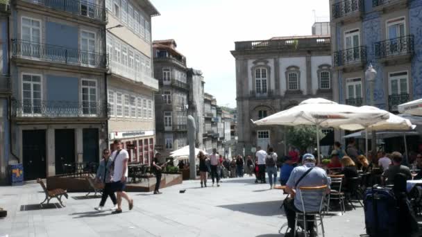 Les gens s'assoient sur les terrasses du café par un après-midi ensoleillé dans le centre historique de Porto, Portugal - 4K — Video