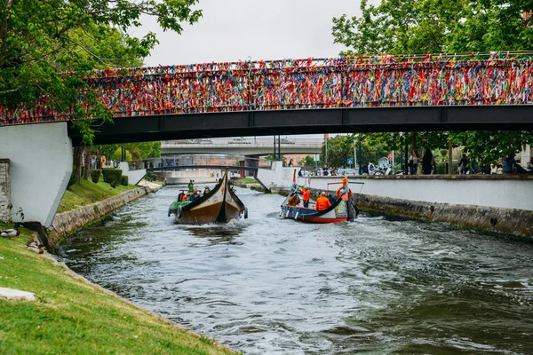 Παραδοσιακό σκάφος, Moliceiro, μεταφορά τουριστών που διέρχεται από γέφυρα που καλύπτεται σε κομφετί στο κανάλι στο Αβέιρο, Πορτογαλία — Φωτογραφία Αρχείου