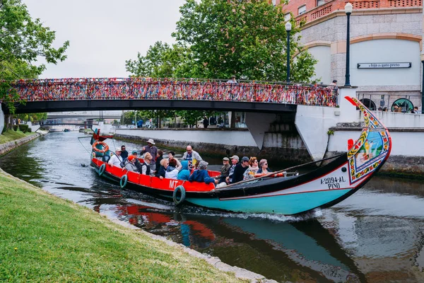 Barco tradicional, Moliceiro, transportando turistas que pasan bajo puente cubierto de confeti en el canal en Aveiro, Portugal — Foto de Stock