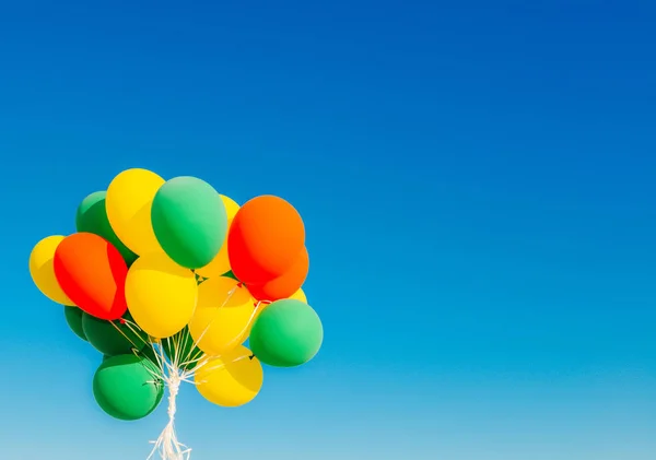 Colourful helium balloons against a blue sky