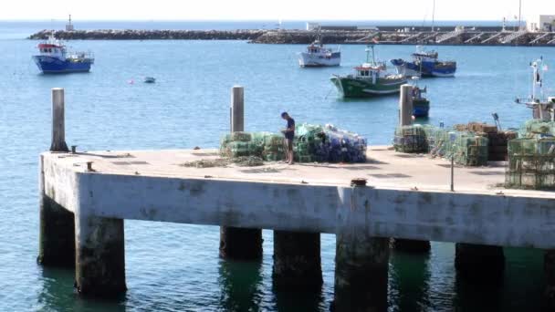 Pescatore scioglie corde su un molo a Cascais, Portogallo con barche da pesca sullo sfondo — Video Stock