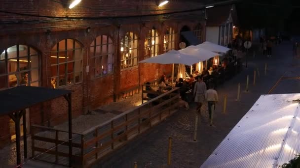 Gente en la terraza del restaurante en LX Factory, un complejo industrial histórico que alberga una variedad de minoristas artísticos y restaurantes únicos en el distrito de Alcantara — Vídeo de stock