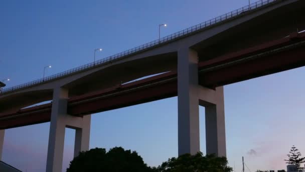 Panning van beneden van de iconische 25 april Bridge in Lissabon, Portugal bij zonsondergang met magenta en roze kleuren op Blue Hour — Stockvideo
