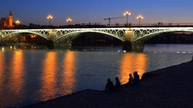 Mavi saat timelapse yayalar ve hareketli tekneler Puente de Triana veya Triana Köprüsü Seville, Endülüs, İspanya