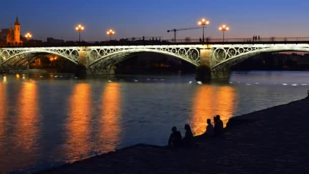 Blå timmen timelapse av fotgängare och rörliga båtar på Puente de Triana eller Triana bron i Sevilla, Andalusien, Spanien — Stockvideo