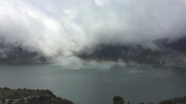 Uitzicht op het Quilotoa-meer, een oude vulkaan en een startpunt voor de Quilotoa Loop-wandeling met mist dicht bij het groene water — Stockvideo