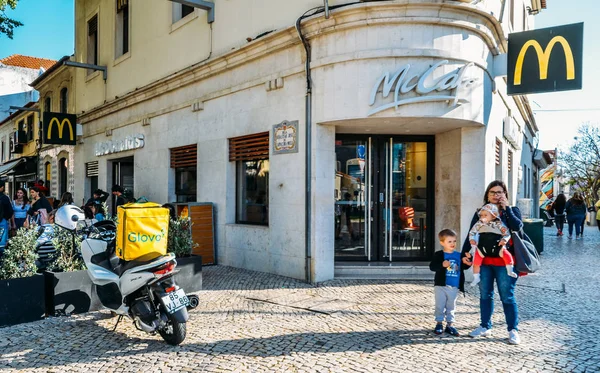 Glovo leverans kurirer på motorcykel och cykel nära McDonald s restaurang. Berömda spanska leverans service Glovo lådor — Stockfoto