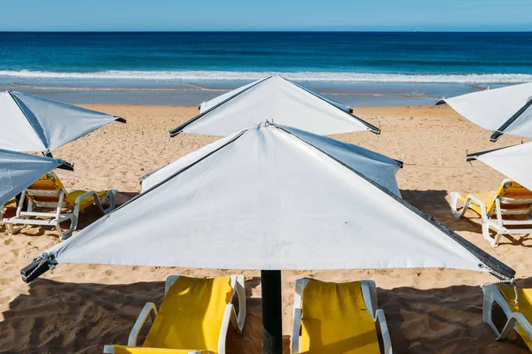 Des chaises longues et un parasol sur une plage déserte concept de vacances parfait — Photo