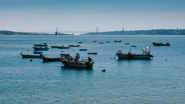 Pequenos barcos de pesca no Tejo com vista para a icónica Ponte 25 de Abril, Lisboa, Portugal - Costa Verde Riviera Portuguesa — Fotografia de Stock