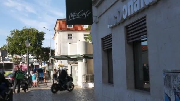 Uber Eats eten delivery driver op een Vespa pick-up eten van een McDonalds fastfoodrestaurant in Cascais, Portugal — Stockvideo