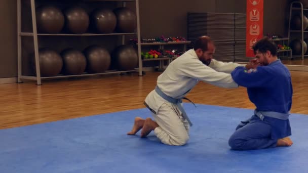 Two men practice Brazilian Jiu-Jitsu sparring, a grappling type martial arts with a kimono gi — Stock Video