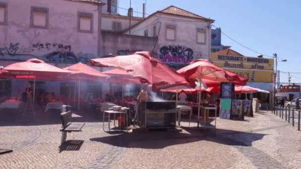 Druk restaurant terras met man koken verse sardines over een hete barbecue in de open — Stockvideo