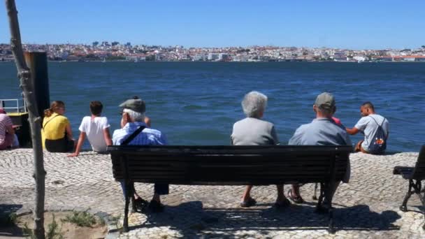 Panning di persone che si rilassano con vista sul fiume Tago sul centro di Lisbona, Portogallo in una giornata estiva soleggiata — Video Stock