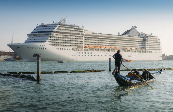 Сопоставление гондолы и огромного круизного судна в канале Джудекка. Старый и новый транспорт по Венецианской лагуне
