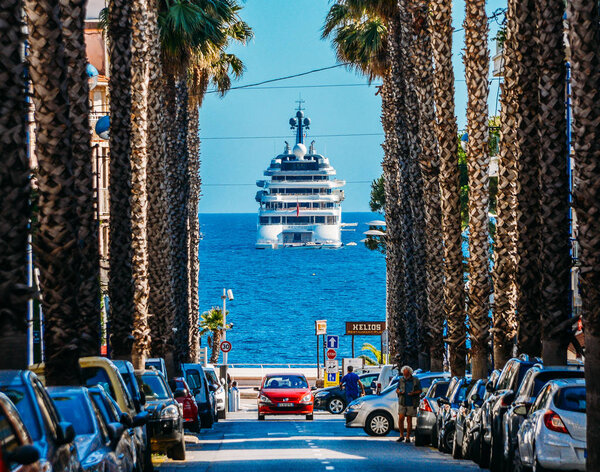 Palm tree lined boulevard leading to luxury yacht on ocean