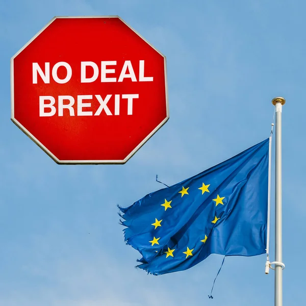 No Deal Brexit written on octagon stop sign with ripped EU flag on background