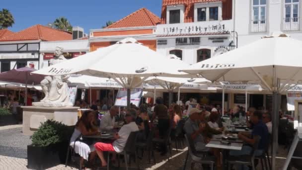 Panning of tourists at Largo Luis de Camoes with cafes and restaurants in Cascais center. People enjoying summer vacations. — Stock Video