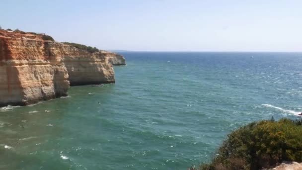 High perspective panning of gold-coloured cliffs, busy beach and turquoise ocean in Benagil beach, Lagoa, Algarve, Portugal — Stock Video