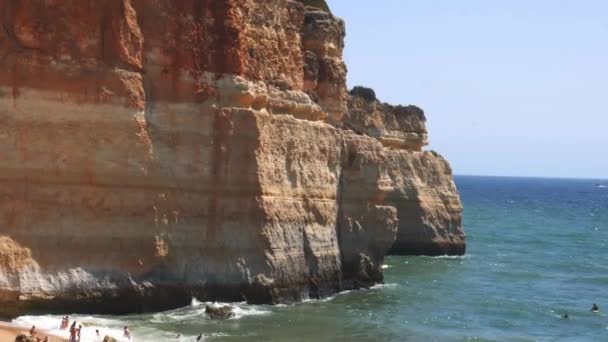 Inclinado hacia abajo de acantilados dorados, playa concurrida y océano turquesa en la playa de Benagil, Lagoa, Algarve, Portugal — Vídeo de stock