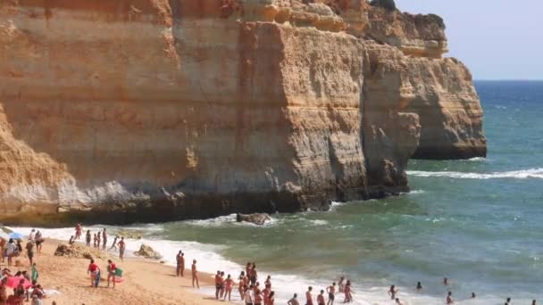 Hoog perspectief op goudkleurige kliffen, druk strand en turquoise Oceaan in Benagil Beach, Lagoa, Algarve, Portugal — Stockvideo
