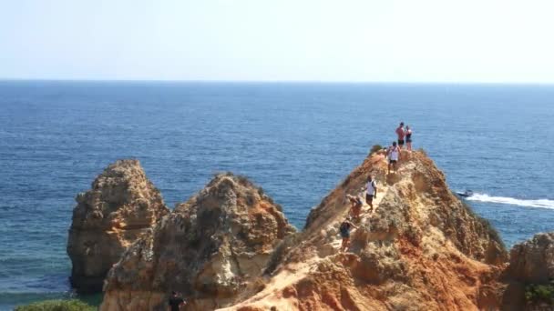 Τουρίστες που κάνουν ορειβασία πάνω και κάτω σε ένα λόφο με θέα στον κόλπο Ponta DA Πιέλαντ, στο Λάγκος, στην Πορτογαλία — Αρχείο Βίντεο