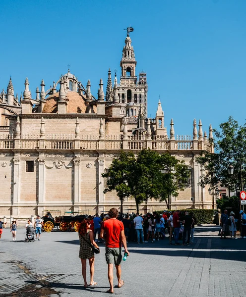 Groep toeristen wordt langs de kathedraal van Sevilla en de Giralda-toren in de Spaanse stad Sevilla — Stockfoto
