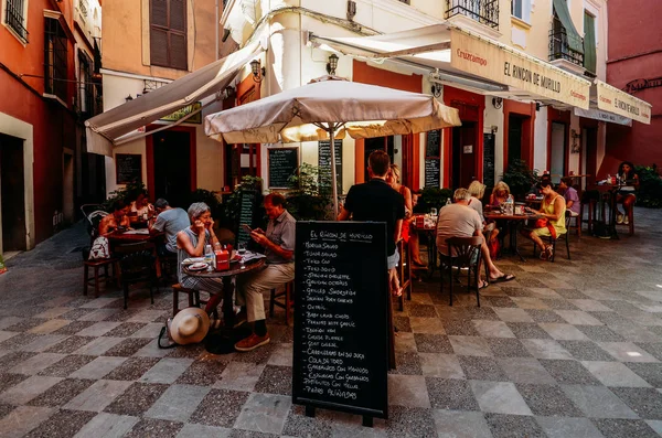 Turistler, İspanya'nın Sevilla bölgesindeki Santa Cruz Yahudi Mahallesi'ndeki bir restoran verandasında yiyecek ve içeceklerin tadını çıkarıyorlar.