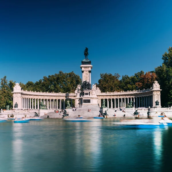 Lange blootstelling van mensen op boten tegenover monument Alfonso Xii in het Parque del Buen Retiro, in Madrid, Spanje — Stockfoto