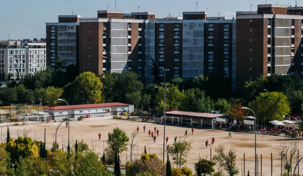 Vista ad alta prospettiva di adolescenti non identificabili su un 11 un lato partita di calcio amatoriale su una zona sabbiosa in un quartiere residenziale — Foto Stock