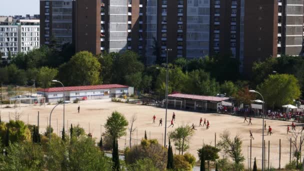 Vista de alta perspectiva de adolescentes no identificables en un 11 un partido de fútbol amateur lateral en una parcela de arena en un barrio residencial — Vídeos de Stock