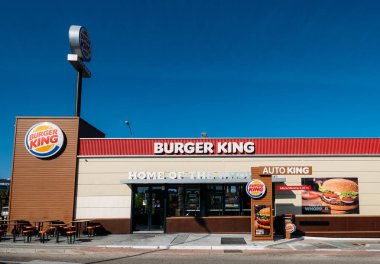 Fast-food Burger King restoranının önünde parlak, çağdaş endüstriyel görünümlü tuğla kaplama ve sipariş noktalarını içeriyor.