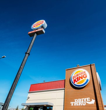 Outside a fast-food Burger King restaurant with a sleek, contemporary futuristic industrial look includes brick cladding and drive-thru order point clipart