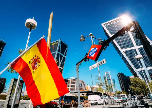 Spanish flag on foreground with Plaza Castilla metro entrance in mid-ground and twin towers in background - Madrid, Spain — Stock Photo, Image