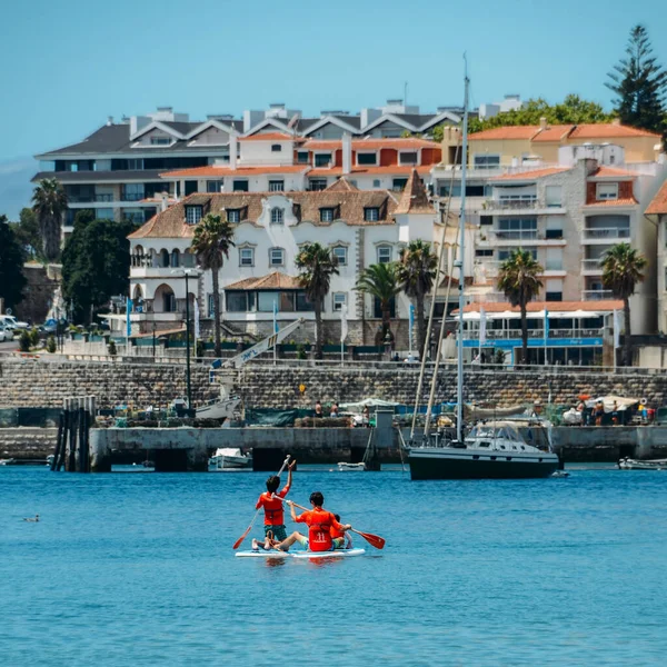 Cascais, Portugal - 28 de julio de 2020: Las personas que disfrutan de stand up paddle en Cascais Bay durante el verano con la costa de Estoril en el fondo — Foto de Stock