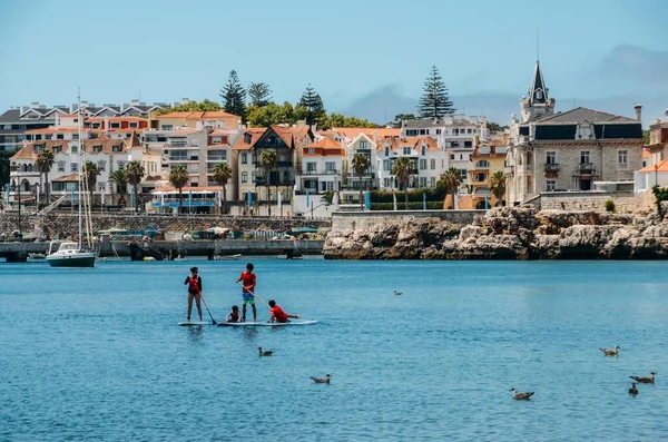 Cascais, Portugal - 28 de julio de 2020: Las personas que disfrutan de stand up paddle en Cascais Bay durante el verano con la costa de Estoril en el fondo — Foto de Stock