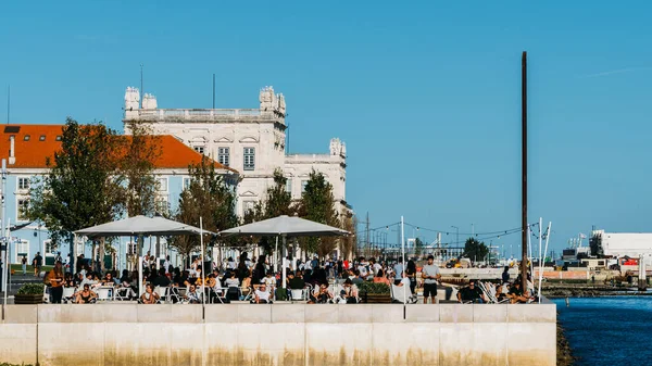Personas relajándose en una cafetería junto al río Tejo en Lisboa, Portugal — Foto de Stock