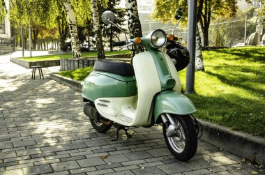 Scooter ön görünüm, ön planda direksiyon simidi ve far. Rıhtımda.
