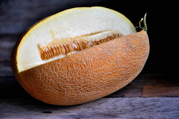 Melon fruit with carved quarters on an old rustic table.