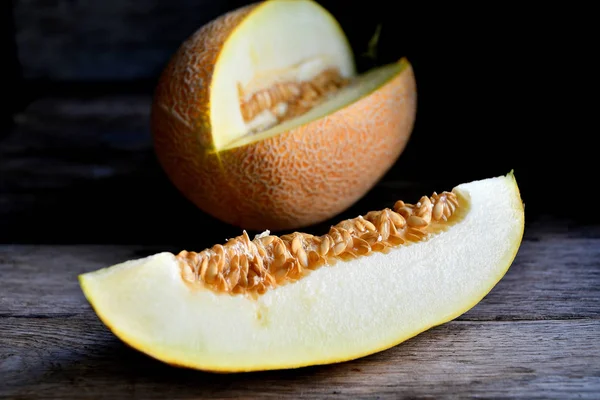 Sliced melon and knife on a wooden table.