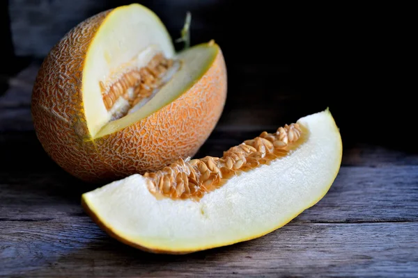 Sliced melon and knife on a wooden table.