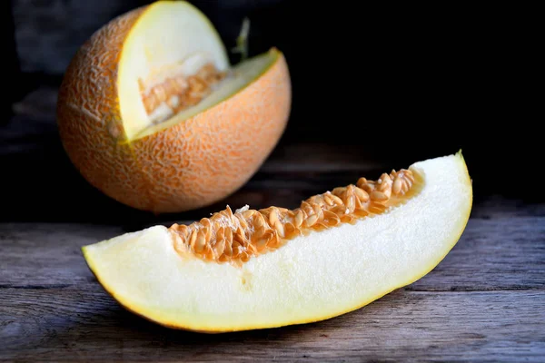 Sliced melon and knife on a wooden table.