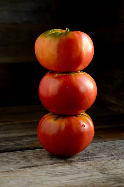 Ripe red tomatoes stacked in an orderly manner on an old rustic table.